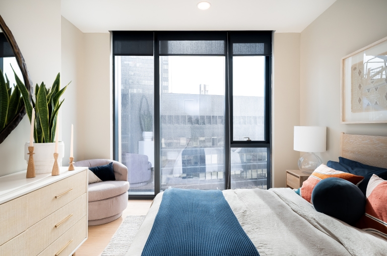 Bedroom with expansive windows, solar shades and hardwood flooring