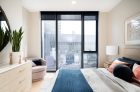 Bedroom with expansive windows, solar shades and hardwood flooring